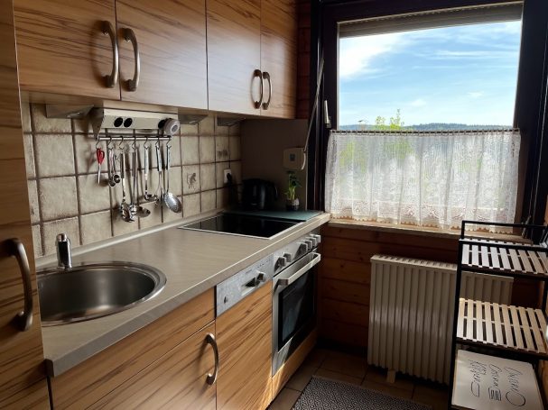 Moderne Küchenzeile mit Spüle, Herd und Fenster, helles Holzdesign.