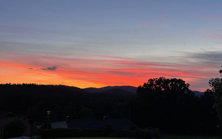 Sonnenuntergang mit lebhaften orange- und rosa Farbverläufen über den Bergen.
